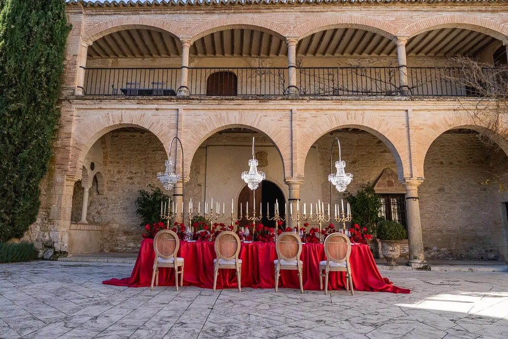 Montaje de mesa imperial para boda con manteleria roja en patio historico